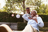 Young black boy embracing grandfather sitting in garden