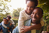 Two young adult black couples piggybacking look to camera