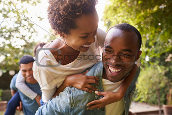 Two adult black couples piggybacking looking at each other