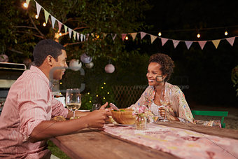 Young African American couple at a dinner table in garden