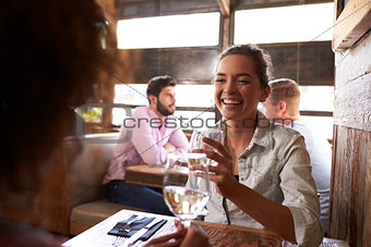 Two female friends having a drink at a table in a bar