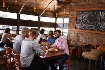 Four male friends sitting at lunch together in a restaurant