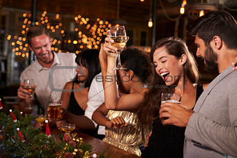 Woman raising a glass at a Christmas party in a bar