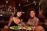 Three female friends enjoying dinner at a restaurant