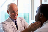 Doctor In White Coat Examining Male Patient In Office
