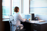 Female Doctor Wearing White Coat In Office Working At Desk