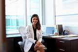 Portrait Of Female Doctor Wearing White Coat In Office