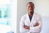Portrait Of Male Doctor Wearing White Coat In Exam Room