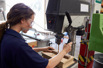 Female Engineer Using Drill In Factory