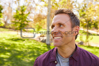 Happy adult man in park looking away from camera, close up