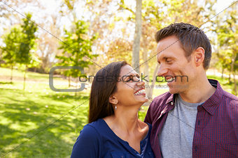 Happy mixed race couple in park looking at each other