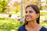 Smiling mixed race woman in park looking away from camera