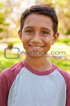 Smiling mixed race boy in park looking to camera, vertical