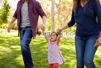 Mixed race couple lifting young daughter in park, crop shot