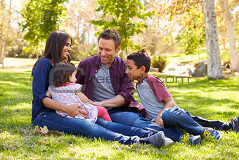 Asian Caucasian mixed race family sitting on grass in a park