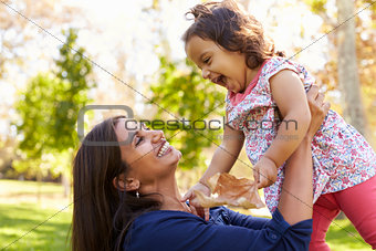 Asian mixed race mum and young daughter playing in park