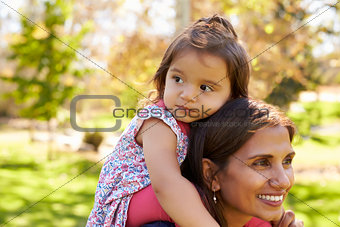 Mixed race mother carrying young daughter on her shoulders