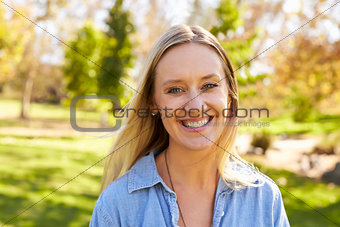 Mid thirties white woman smiling to camera in a park