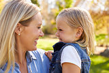 Blonde woman and young daughter look at each other, close up