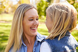 Blonde woman and young daughter laughing together, close up