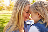 Blonde woman and her young daughter touching heads together