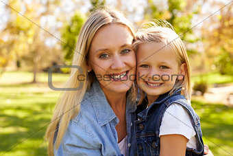 Mother and young daughter smiling to camera, heads together