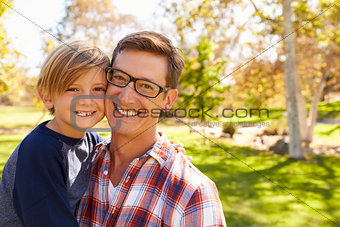 Father and seven year old son smiling to camera in a park