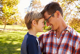 Father and young son in a park, heads together, side view
