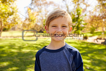 Seven year old Caucasian boy in a park smiling to camera