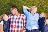 Young white family lying on grass in a park, waist up