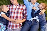 Young white family lying on grass embracing, crop shot