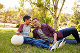 Father and son relaxing with soccer ball in a park, close up
