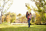 Asian Caucasian woman carrying her young daughter in a park