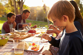 Young boy eating at a picnic table in a park