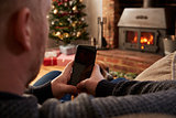 Man Using Mobile Phone In Room Decorated For Christmas