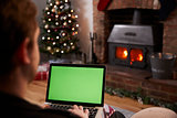 Man Using Laptop In Room Decorated For Christmas