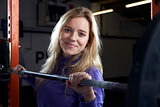 Portrait Of Young Woman In Gym Lifting Weights On Barbell