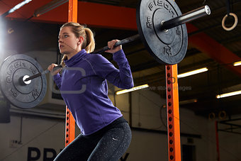 Woman In Gym Lifting Weights On Barbell