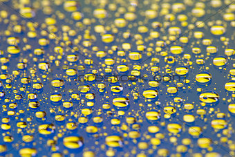 the Abstract blue-yellow background with gradient color water drops on glass with reflection, bockeh, macro