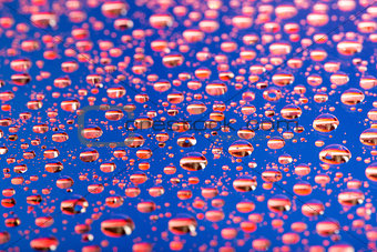 the Abstract blue-red background of water drops on glass with reflection green macro