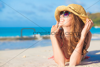woman in bikini and straw hat lying on tropical beach