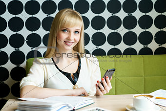 Girl sitting in cafe holds a smartphone