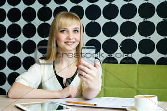 Girl sitting in cafe holds a mobile phone