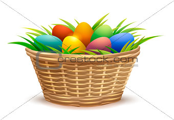 Wicker basket full of Easter eggs on grass