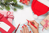Female writing christmas greeting card and gift wrapping