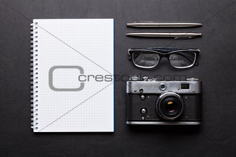 Office desk with camera, notepad, glasses, pen