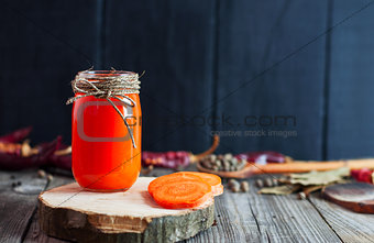 Jar of fresh carrot juice on a wooden surface