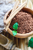 Cocoa powder and cinnamon sticks in a wooden bowl.