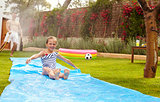 Father And Daughter Having Fun On Water Slide In Garden