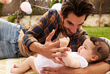 Father With Baby Playing On Rug In Garden Together